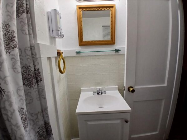 White bathroom with sink, mirror, and shower curtain.